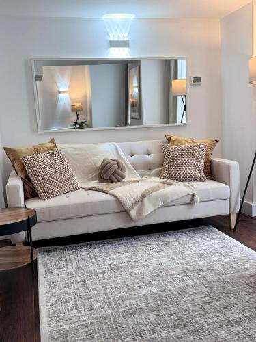 a large white couch in a living room with a mirror at Luxury 2Bed, 2Bath Flat in Greenwich London in Woolwich