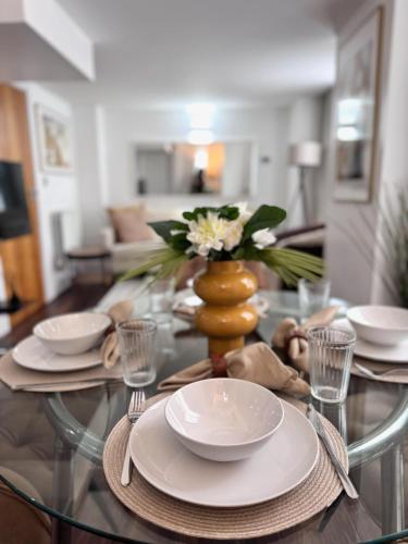 a glass table with plates and a vase with flowers at Luxury 2Bed, 2Bath Flat in Greenwich London in Woolwich