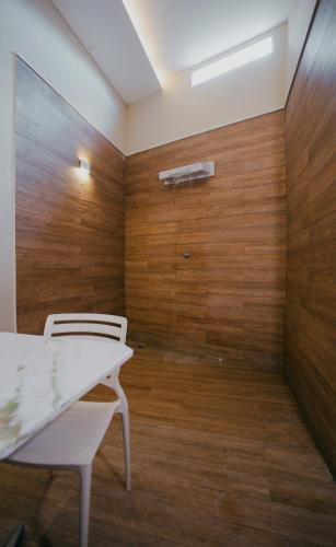 a room with two white chairs and a wooden wall at Trópicos Motel in Natal