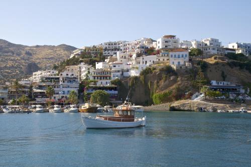 a boat in a body of water with houses at Saitis Luxury Residence - 15 min from Matala - Kommos - Kalamaki Beach in Tympáki
