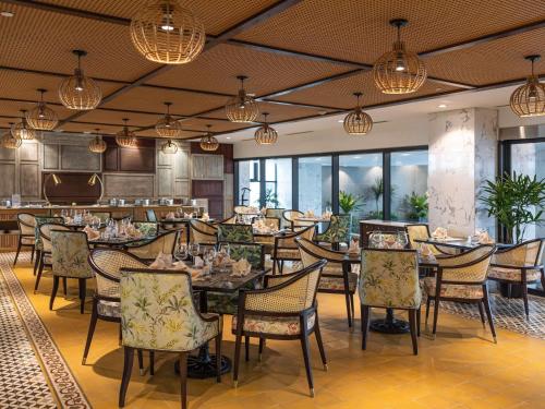 a dining room with tables and chairs and lights at Mövenpick Living West Hanoi in Hanoi