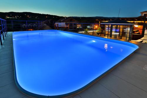 a blue swimming pool on a roof at night at Garni Hotel Zen in Niš