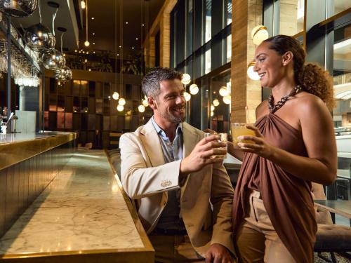 a man and a woman sitting at a bar with drinks at Number 11 St Julian's Malta - Handwritten Collection in St Julian's