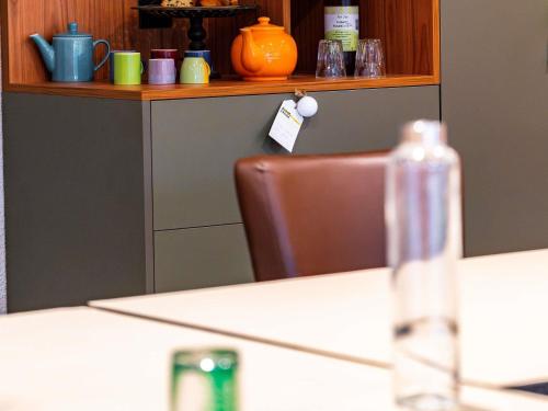 a table with a chair and a bottle on a table at greet Hotel Massieux Lyon Nord in Massieux