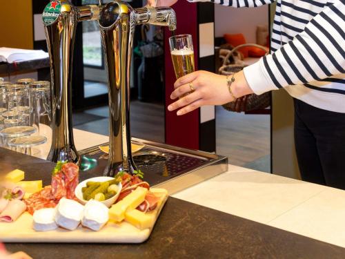 a person holding a glass of champagne next to a plate of food at greet Hotel Massieux Lyon Nord in Massieux