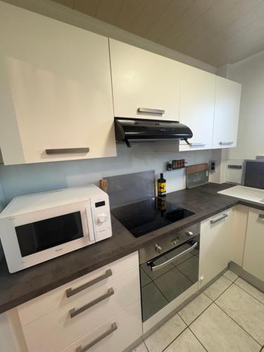 a kitchen with white cabinets and a microwave oven at Le Cerf in Wintzenheim