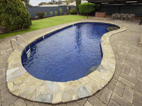 a swimming pool with a stone walkway around it at Breakfree Port Pirie in Port Pirie