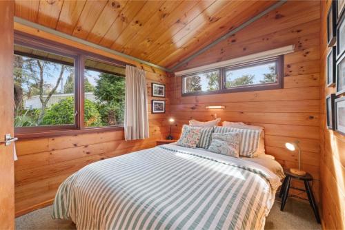 a bedroom with a bed in a wooden cabin at Hatepe Lake Taupo Retreat in Motutaiko Island