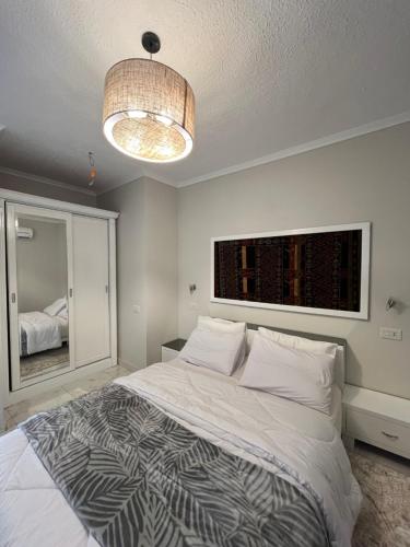 a bedroom with a large bed and a chandelier at Evoke suites apartment in central madinaty 2 bedroom in Madinaty