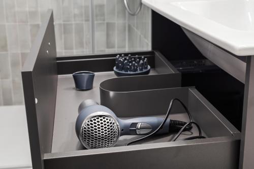 a gray hair dryer in a box under a sink at Maria Blick - Design Apartments am Wörthersee in Maria Wörth