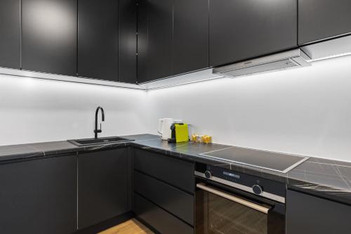 a kitchen with black cabinets and a sink at Maria Blick - Design Apartments am Wörthersee in Maria Wörth