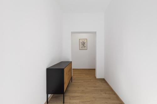 a room with a black dresser and a white wall at Maria Blick - Design Apartments am Wörthersee in Maria Wörth