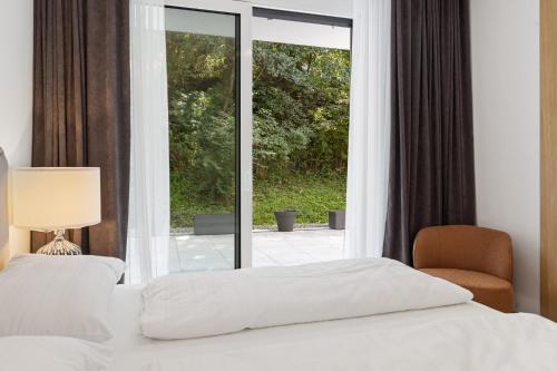 a bedroom with a bed and a window and a chair at Maria Blick - Design Apartments am Wörthersee in Maria Wörth