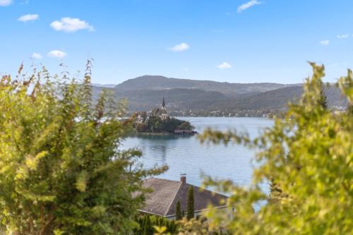 an island in the middle of a lake with a church at Maria Blick - Design Apartments am Wörthersee in Maria Wörth