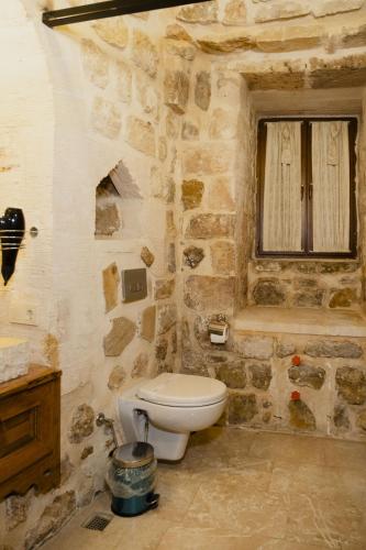 a stone bathroom with a toilet and a window at Kadimhan konağı otel in Mardin