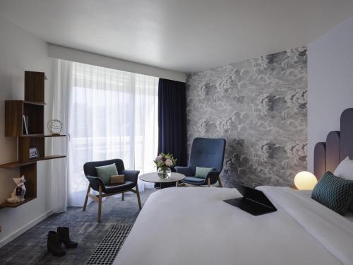 a hotel room with a large bed and two chairs at Mercure Aix-les-Bains Domaine de Marlioz Hôtel & Spa in Aix-les-Bains
