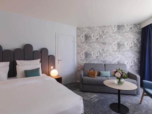 a bedroom with a large bed and a couch at Mercure Aix-les-Bains Domaine de Marlioz Hôtel & Spa in Aix-les-Bains