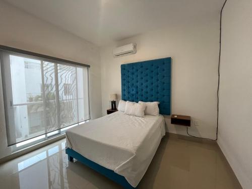 Confortable casa en Cozumel, cerca del mar #10 في كوزوميل: غرفة نوم مع سرير مع اللوح الأمامي الأزرق ونافذة