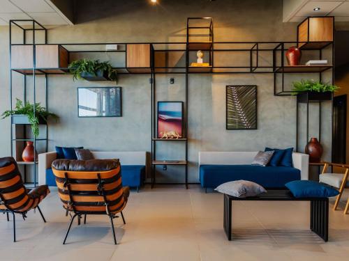 a living room with a blue couch and chairs at ibis Lavras in Lavras