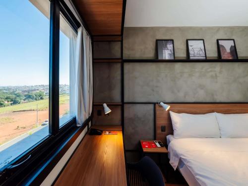 a bedroom with a bed and a large window at ibis Lavras in Lavras