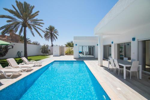 een villa met een zwembad en een patio met stoelen en een tafel bij Villa Dar Salama, 3 Chambres, Plage à 5 minutes in Midoun