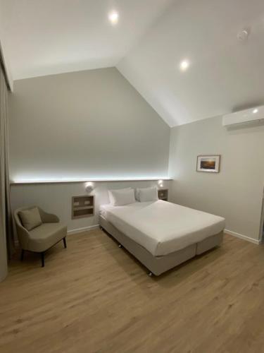 a white bedroom with a bed and a chair at Brooklands Of Mornington in Mornington