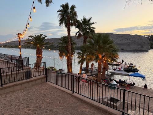 a beach with palm trees and a boat in the water at RIV A HOLIC in Bullhead City