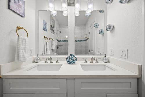 un bagno bianco con due lavandini e un grande specchio di Olde Town Gem 5 Tvs Hot Tub & Game Yard ad Arvada