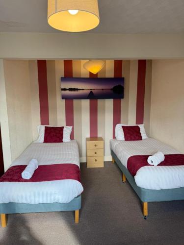 zwei Betten in einem Zimmer mit rot-weißen Streifen in der Unterkunft VERNON Hotel in Blackpool