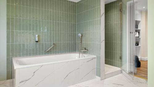 a bath tub in a bathroom with green tiles at Hotel Bristol Berlin in Berlin