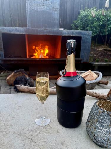 a wine bottle and a glass on a table with a fireplace at Sunny St Heliers in Auckland