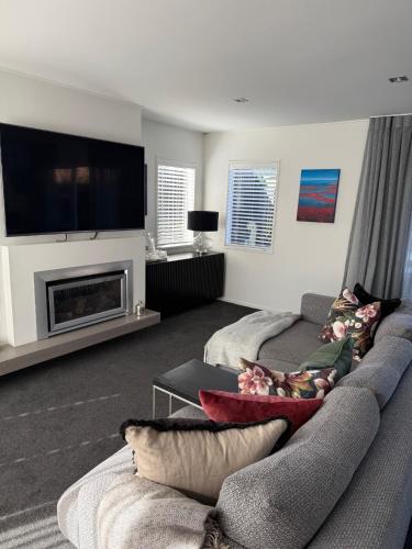 a living room with a couch and a flat screen tv at Sunny St Heliers in Auckland