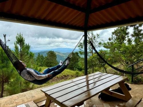 a man swinging in a hammock on a porch at Cabaña CRISTAL Jacuzzi Paisaje Vista Increible en la Montaña C&M 