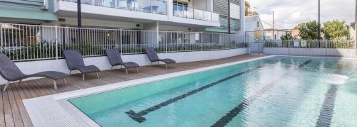 a swimming pool with chairs next to a building at Freo Family Escape Pool, Port Views & Free Park in Fremantle