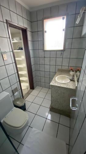 a bathroom with a toilet and a sink and a window at Cantinho do Litoral Salvador in Salvador