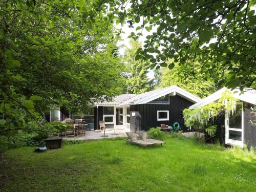 a black shed with a picnic table in the yard at 8 person holiday home in Tisvildeleje in Tisvildeleje