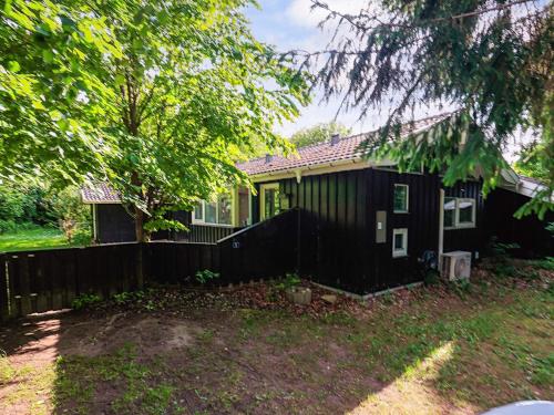 a black house with a fence in the yard at 8 person holiday home in Tisvildeleje in Tisvildeleje