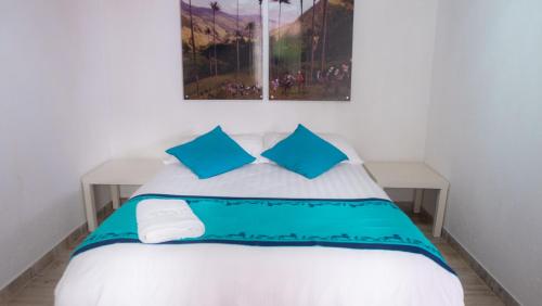 a bedroom with a white bed with blue pillows at Hostal Ciudad de Segorbe in Salento