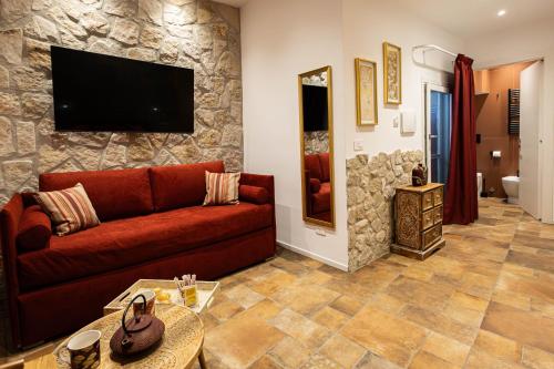 a living room with a red couch and a stone wall at Dimora Milù in Foggia
