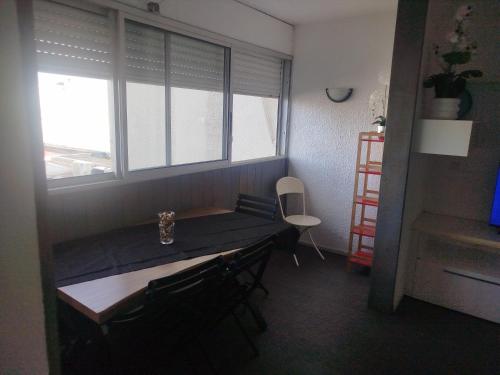 a table and chairs in a room with windows at Le regard sur la marina in Les Trois-Îlets