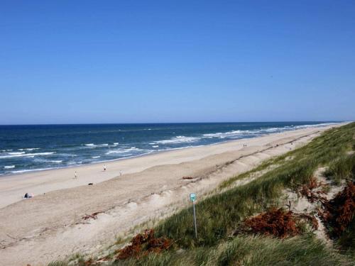 a beach with people walking on the sand and the ocean at Charming Retreat in Ringkobing - By Traum Ferienwohnungen in Ringkøbing