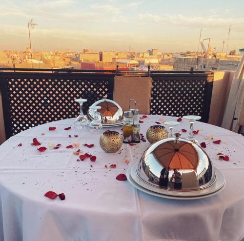 un tavolo con una tovaglia bianca con rose sopra di Riad ABBASSIA Marrakech Premiere - Authentic Medina Experience a Marrakech