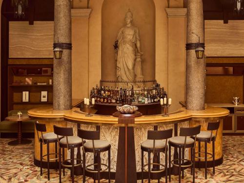 a bar with stools and a statue of a woman at Orient Express La Minerva in Rome