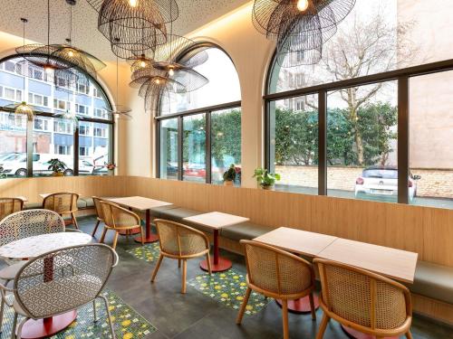 a restaurant with tables and chairs and windows at Ibis Styles Strasbourg Centre République in Strasbourg