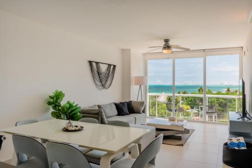 a living room with a table and a large window at Seacost Beachfront 2BDR with pool by Casa Paraiso in Cancún