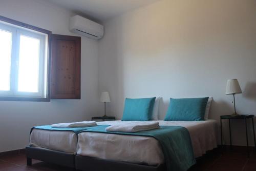 a bedroom with a bed with blue pillows and a window at Quinta do Sobreiro in Reguengos de Monsaraz