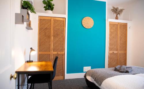 een slaapkamer met een bureau, een bed en een blauwe muur bij The Channel View, 4 bedrooms, 4 beds, FREE parking, 3 minutes from the beach in Eastbourne