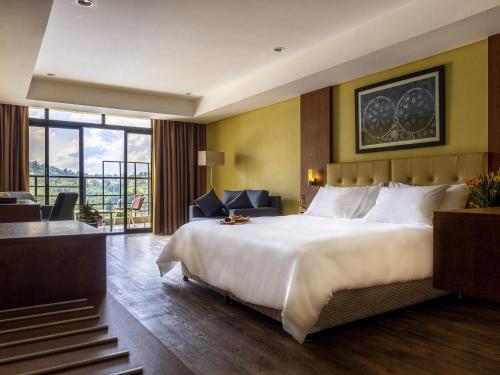 a hotel room with a large bed and a balcony at Mantis Kivu Marina Bay Hotel in Muhari