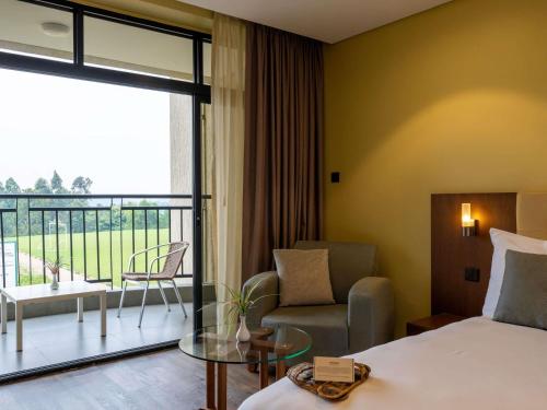 a hotel room with a bed and a balcony at Mantis Kivu Marina Bay Hotel in Muhari