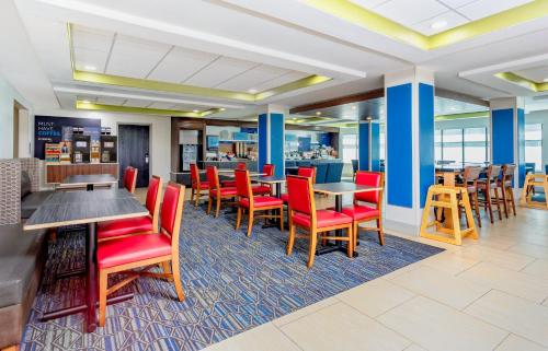 a dining area with red chairs and tables in a restaurant at Holiday Inn Express Hotel & Suites Jacksonville-Blount Island by IHG in Jacksonville